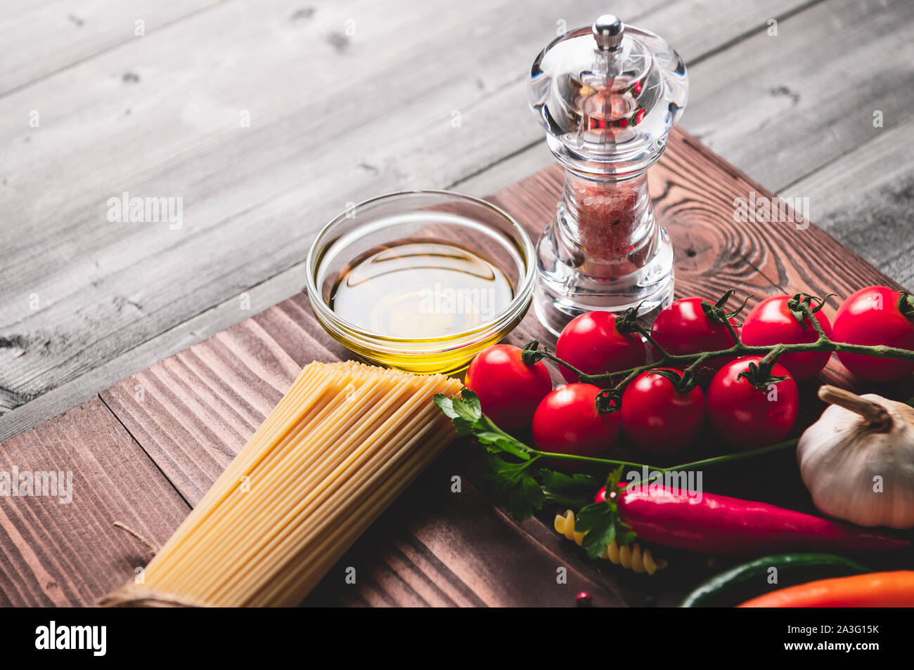 Gustosi piatti appetitosi italian spaghetti ingredienti per cucina cucina con pomodoro, formaggio parmigiano, olio d'oliva, fettuccine e basilico sul legno marrone Foto Stock