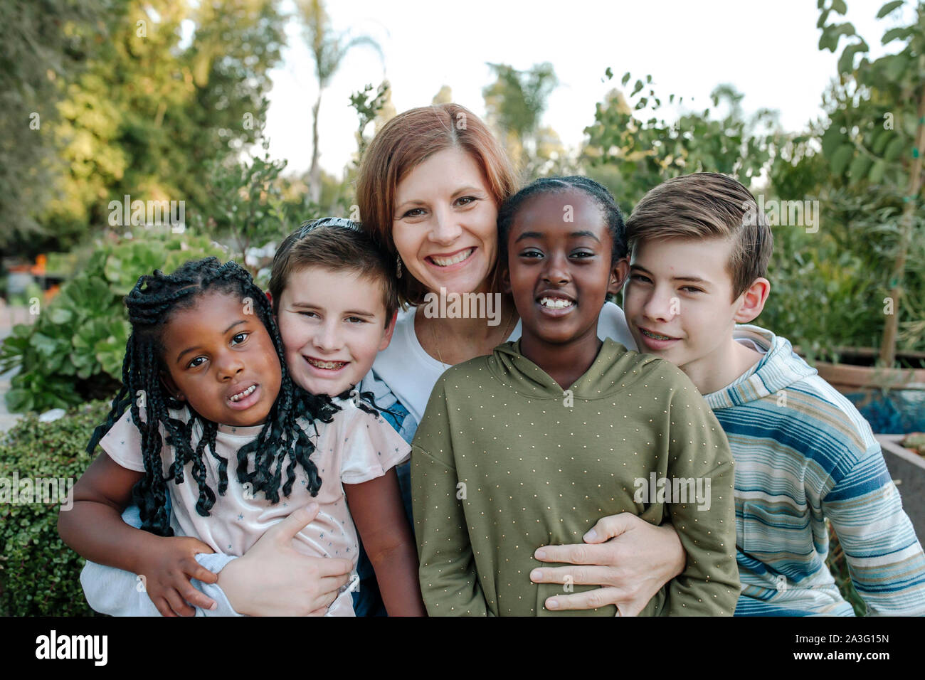 Sorridente mid-40's mom & e quattro bambini felici- razza mista famiglia Foto Stock