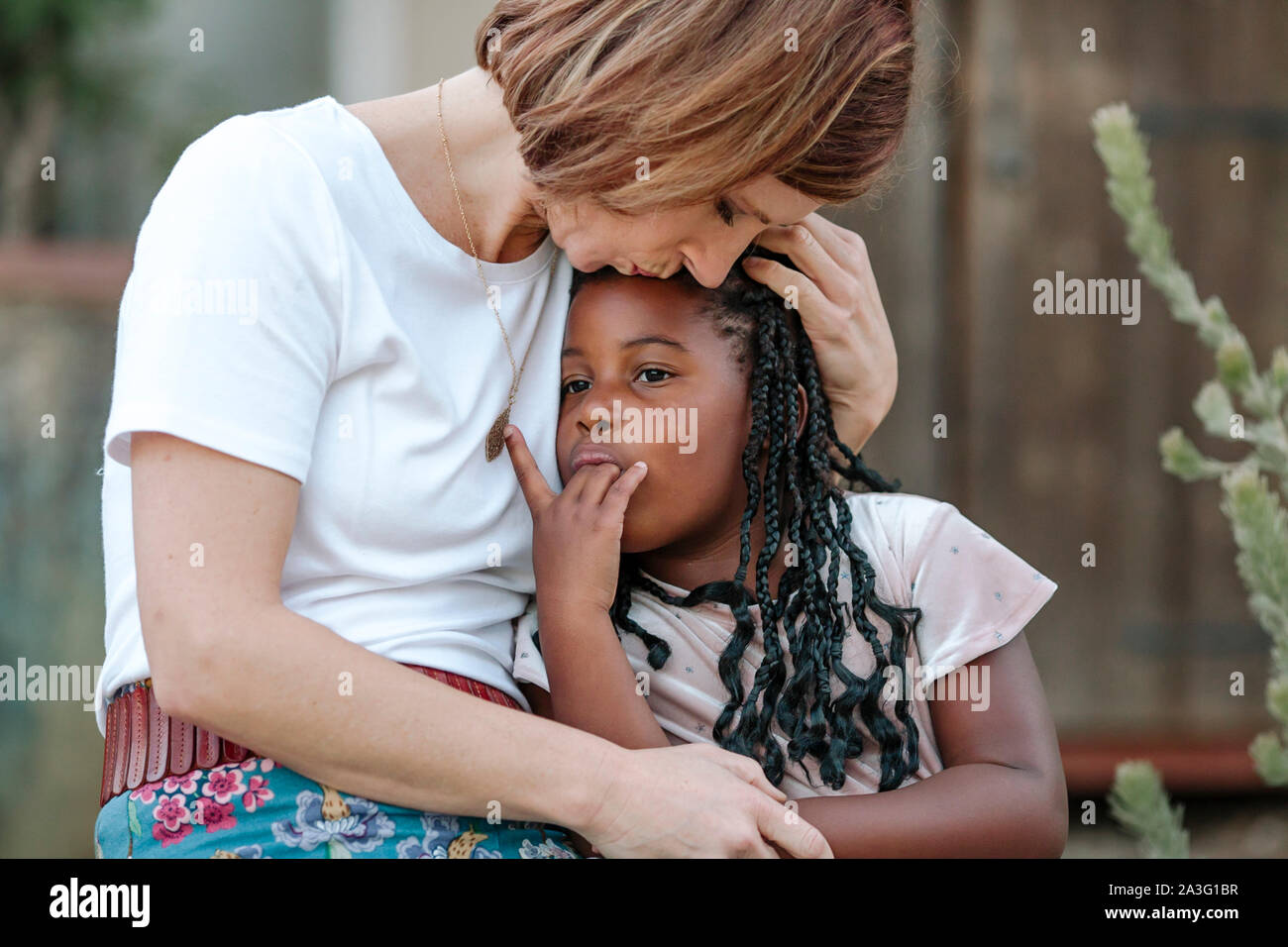 Amare MOM raccoglie preziosi giovane figlia di nero con lunghe trecce Foto Stock