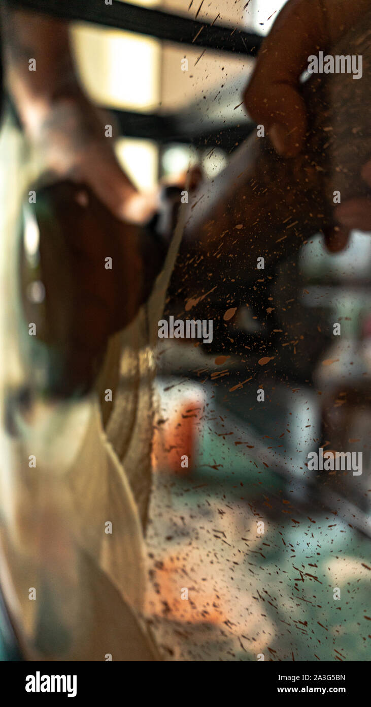 Close-up su schizzi e meccanico con le mani in mano utilizzando vetro professionale utensile di lucidatura per rimuovere graffi Foto Stock