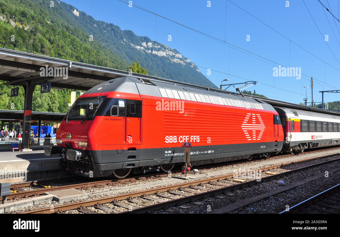 Classe Re 460 locomotiva elettrica con un express treno passeggeri a Interlaken Ost stazione ferroviaria, Oberland bernese, Svizzera Foto Stock