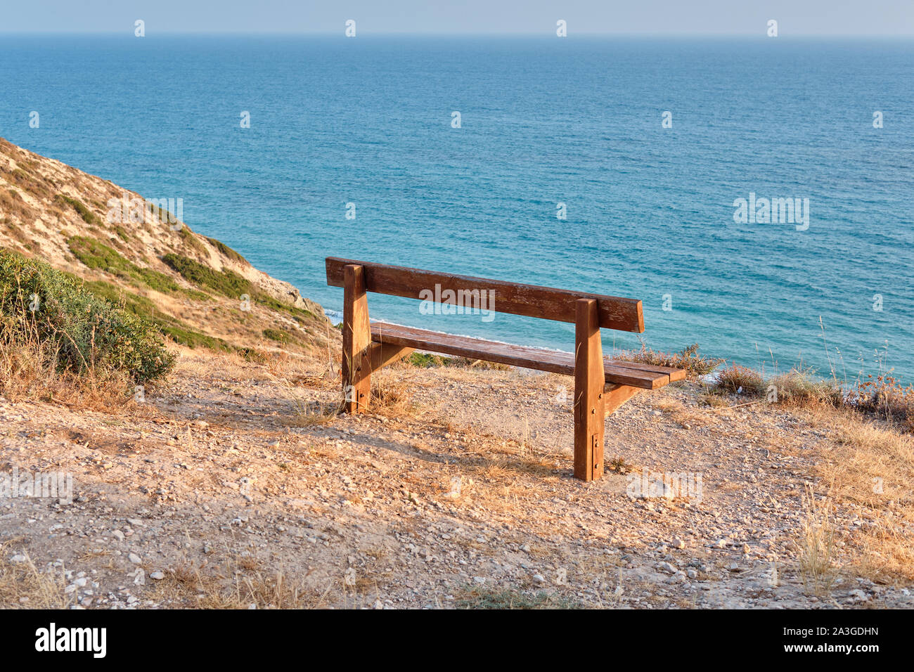 Inquadratura ravvicinata di una vecchia panca di legno in piedi su una montagna presso la spiaggia di azzurro mare mediterraneo e circondato da una natura bellissima di Cipro. A Foto Stock