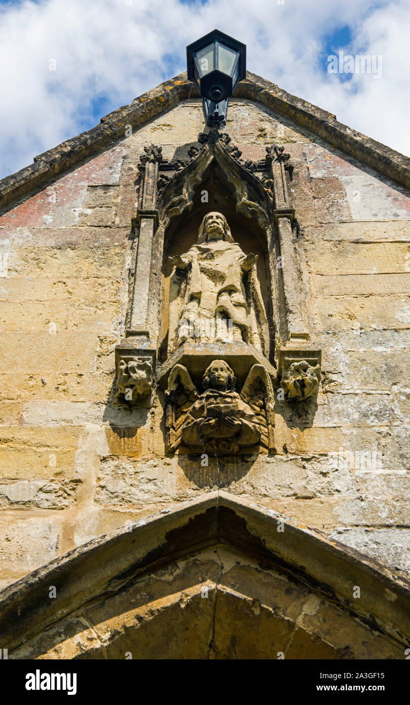 Chiesa parrocchiale di St Andrew Castle Combe nel Wiltshire che mostra la scultura di Gesù sopra il portico porta Foto Stock