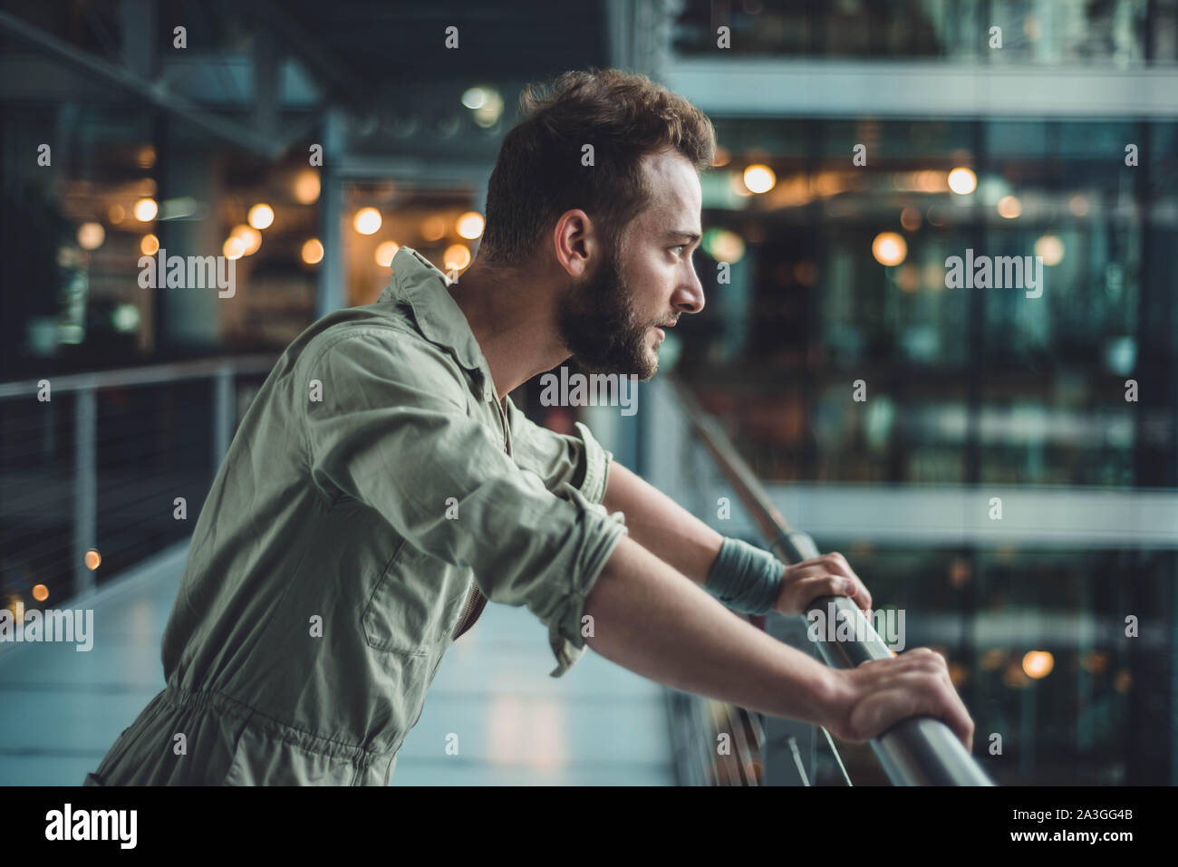 L'uomo si appoggia su una ringhiera e guarda avanti con uno sguardo intenso. Forse preparandosi a fare la cosa dura. Foto Stock