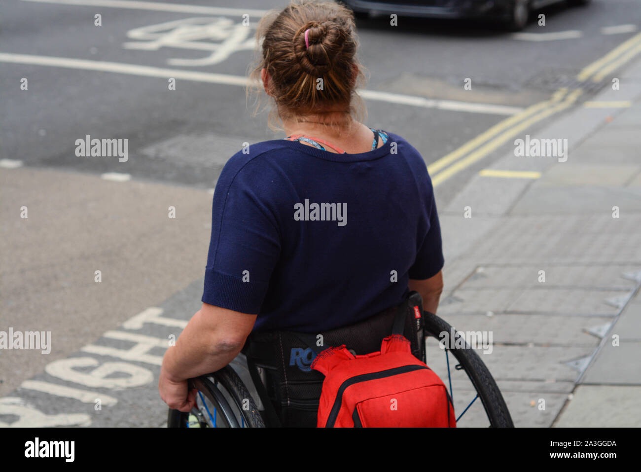 Donna disabili in carrozzella è attraversare la strada da solo Foto Stock