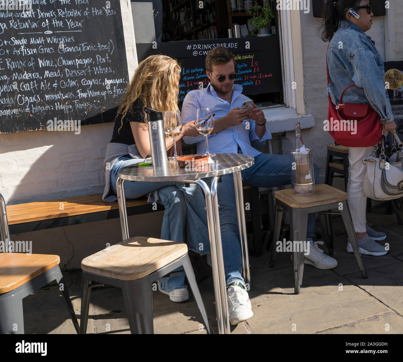 L uomo e la donna sedeva al tavolo con bottiglia e bicchieri di bevande della città di Cambridge 2019 Foto Stock