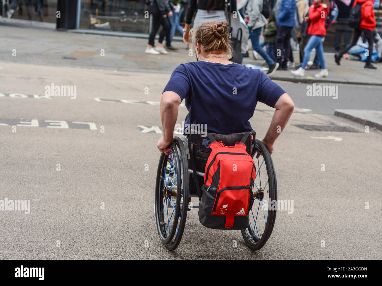 Donna disabili in carrozzella è attraversare la strada da solo Foto Stock