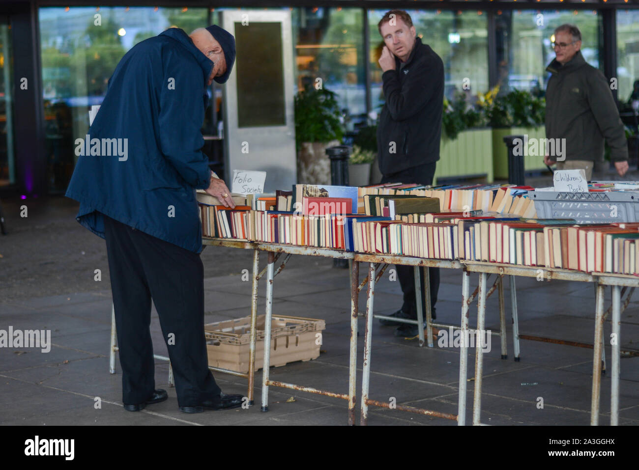Vecchia persona scegliendo libro da una seconda mano book shop installato in strada Foto Stock