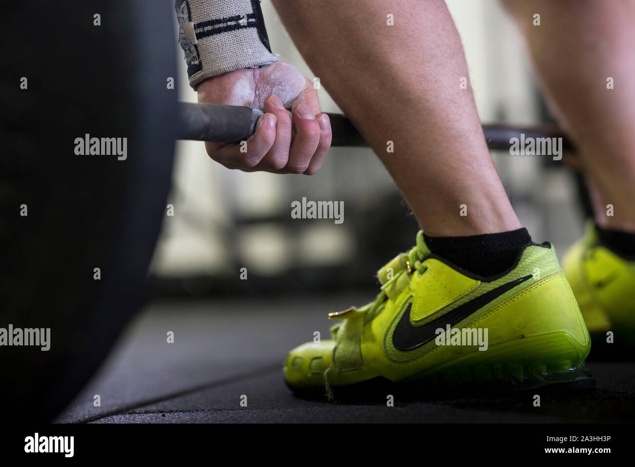 Un bianco giovane atleta maschio esegue diversi impianti di risalita e il peso corporeo dei movimenti in un ambiente palestra. Foto Stock