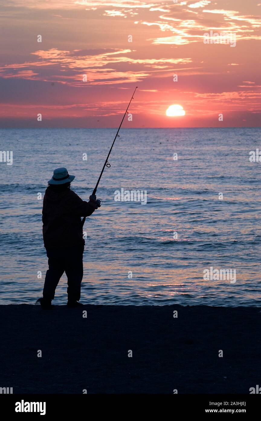 Silhouette pescatore sulla spiaggia al tramonto Foto Stock