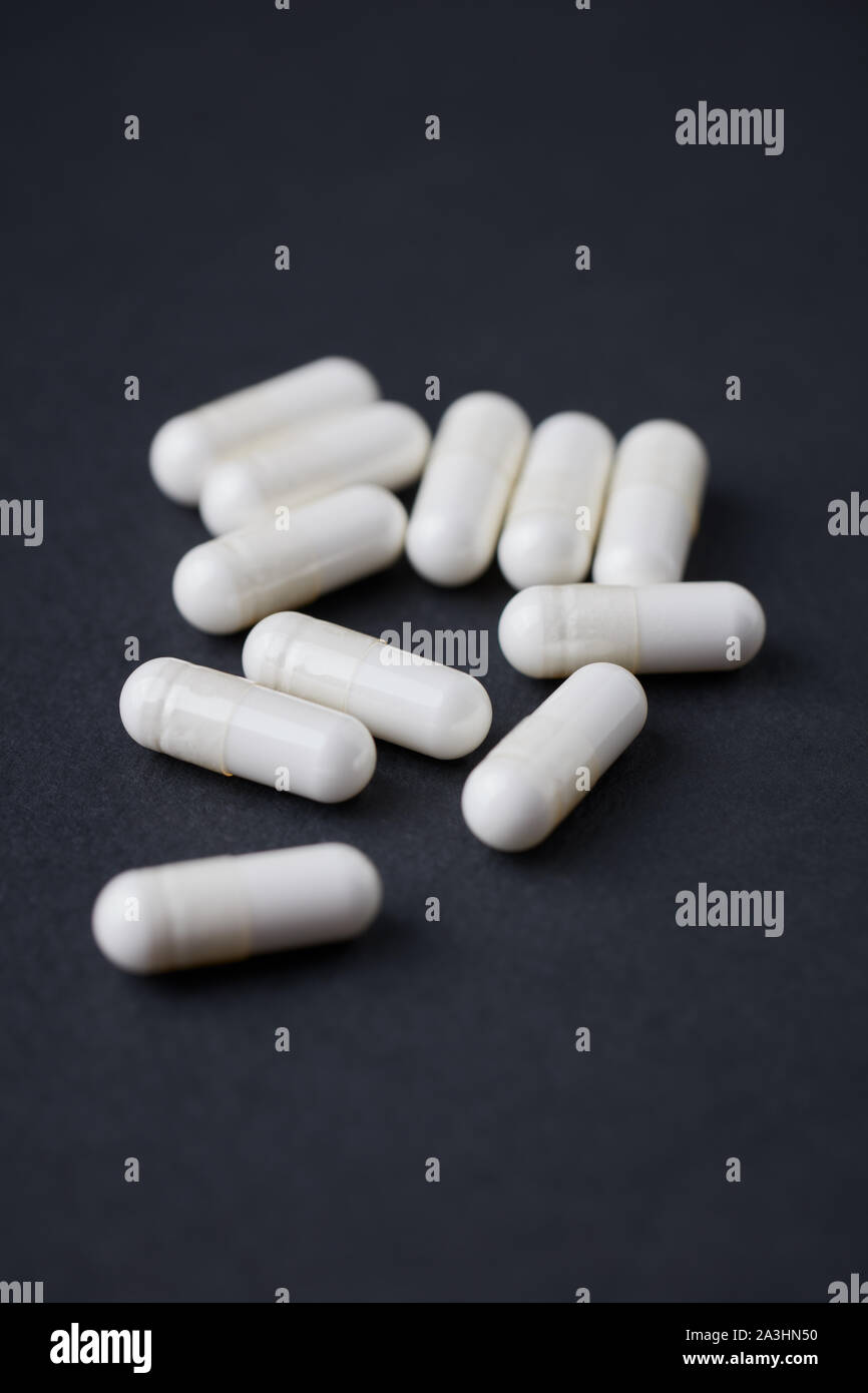 Le capsule di arginina. Nero lo sfondo della carta. Close up. Copia dello spazio. Foto Stock