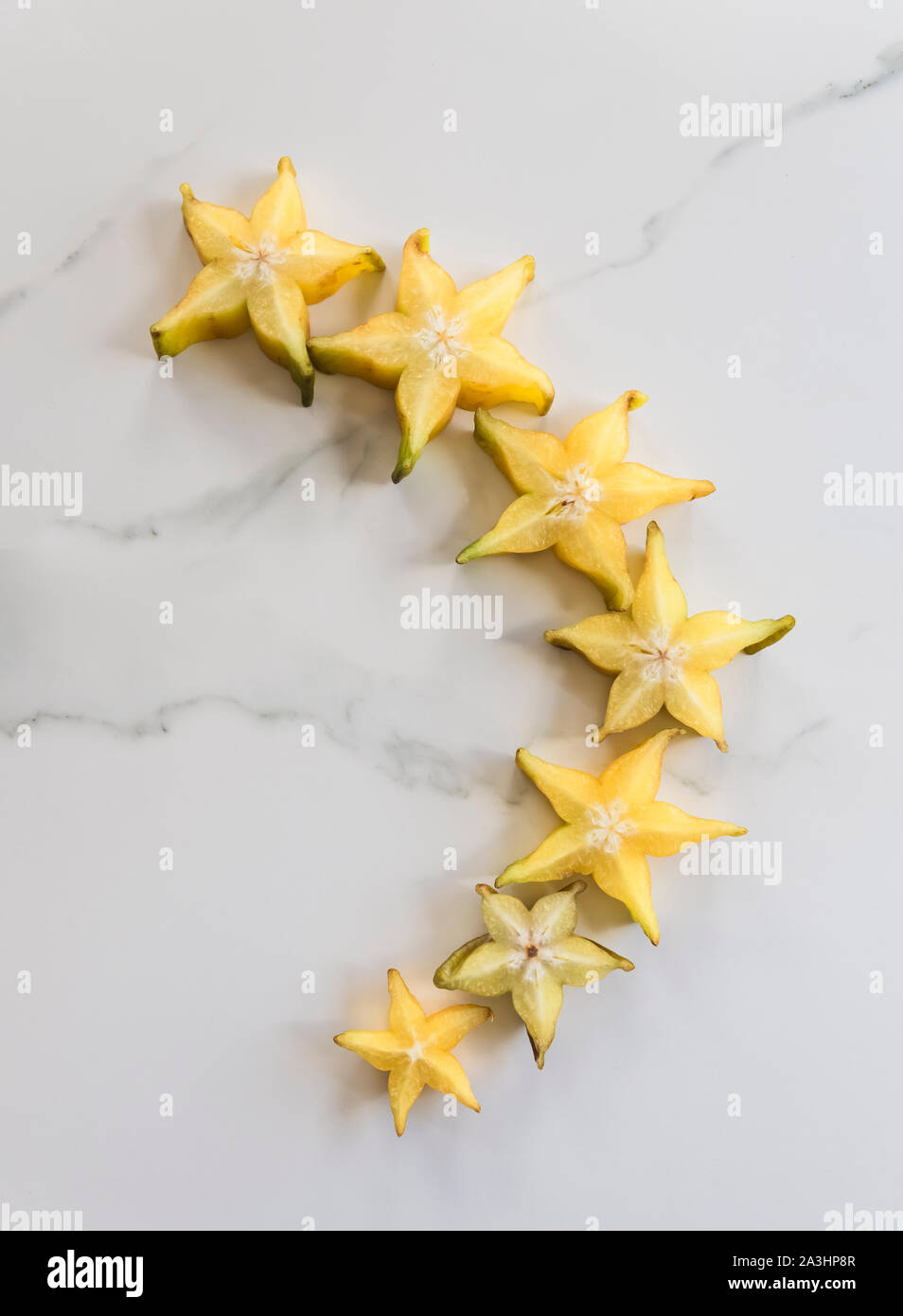 Fette di star fruit, carambole, disposti su marmo bianco dello sfondo. Foto Stock