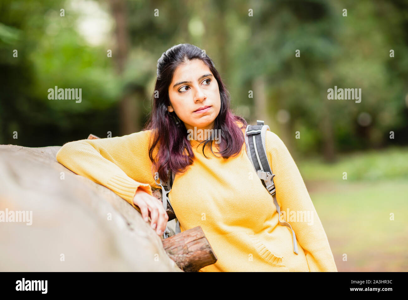 Giovane donna escursionismo e stare vicino a un tronco di albero stanco Foto Stock