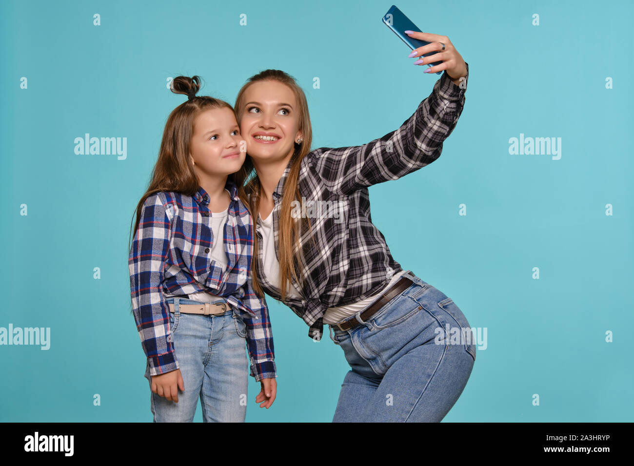 Mamma e figlia vestito in camicie a scacchi e blue jeans denim stanno  rendendo selfie mentre posa contro un blu di sfondo per studio. Close-up  shot Foto stock - Alamy