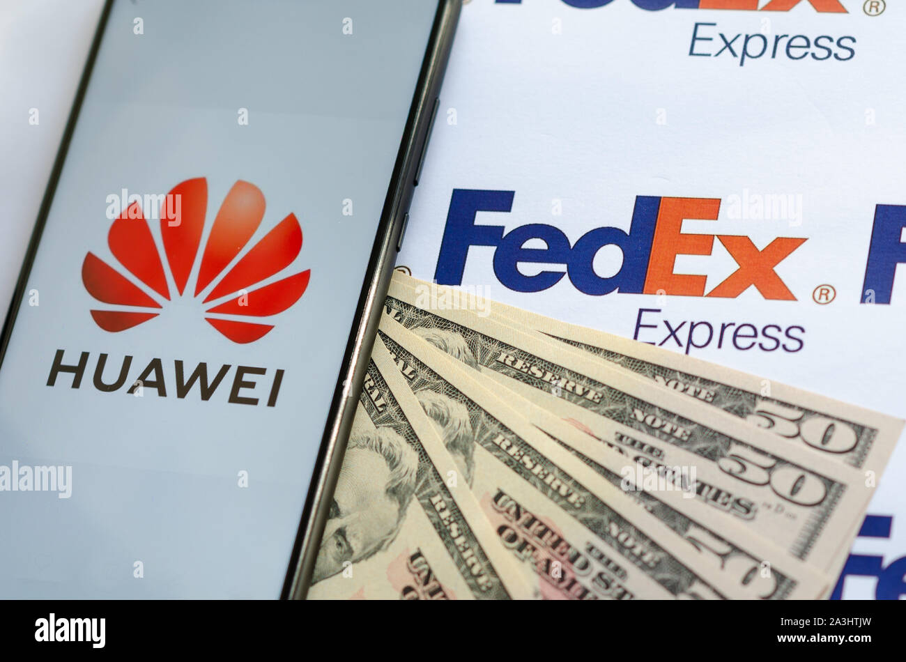 Huawei smartphone con logo sul pacco FedEX logo con dollari Usa.Questa foto concettuale illustra USA - Cina guerra commerciale e inchieste in corso Foto Stock