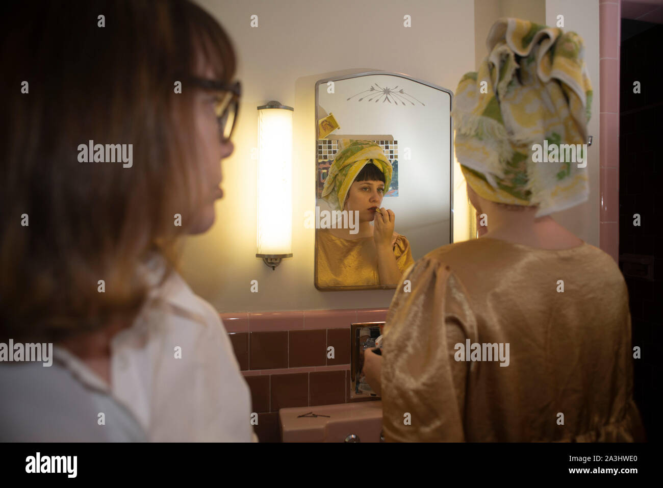 Donna che guarda un'altra donna Rossetto nello specchio del bagno Foto Stock