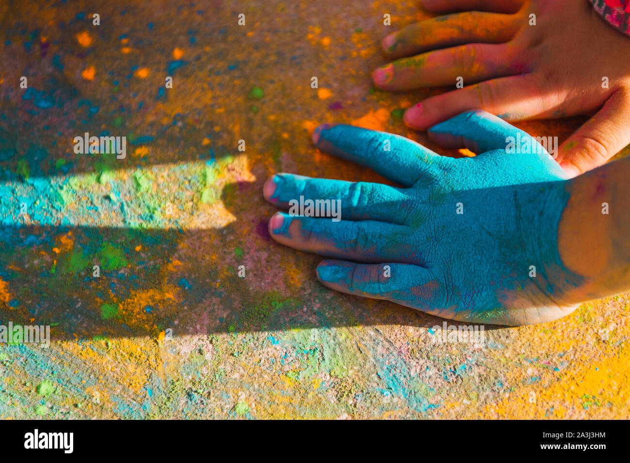 I bambini con le mani in mano riempiti con polveri colorate sul pavimento rosso Foto Stock