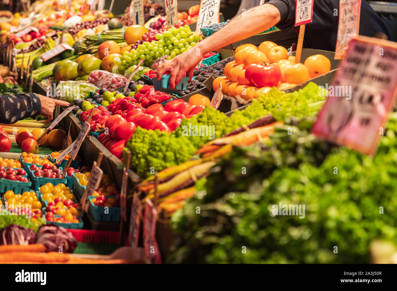 Stati Uniti d'America, nello Stato di Washington, Seattle, il Pike Place Market. Agosto 15, 2019. Venditore a vendere prodotti freschi. Foto Stock