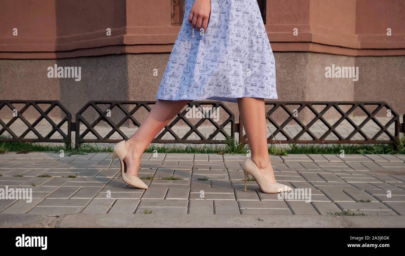 Signora in vestito blu stupendo gambe in beige tacchi alti a piedi lungo la strada marciapiede piastrellato sul giorno caldo vicino a bassa angolazione Foto Stock