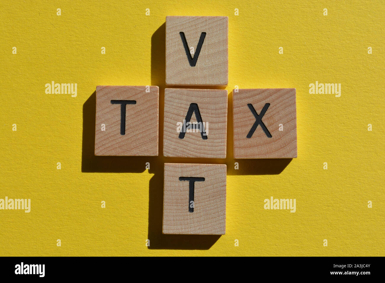 Imposta e l'acronimo IVA Imposta sul valore aggiunto in 3d alfabeto di legno lettere su un brillante sfondo giallo Foto Stock