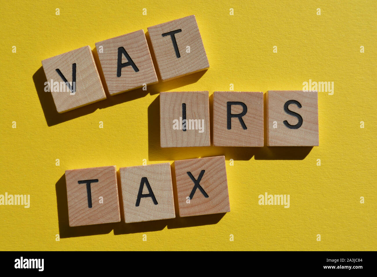 Tasse e gli acronimi di iva e IRS, imposta sul valore aggiunto e Internal Revenue Service in 3d alfabeto di legno lettere isolate su un brillante sfondo giallo Foto Stock