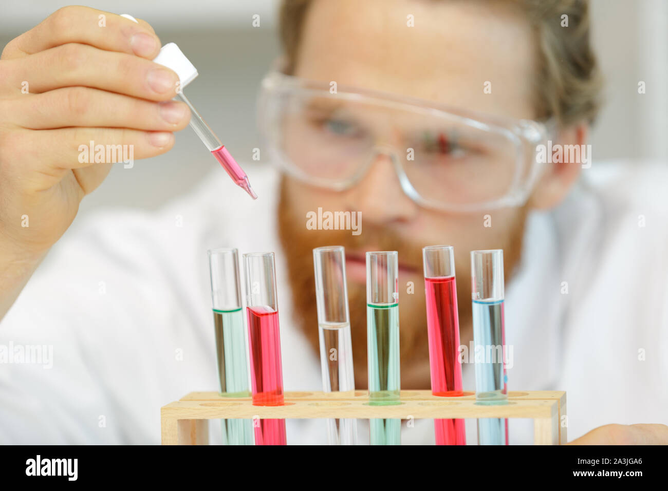 Lavoratore di ricerca fare esperimenti con liquido chimico in laboratorio Foto Stock