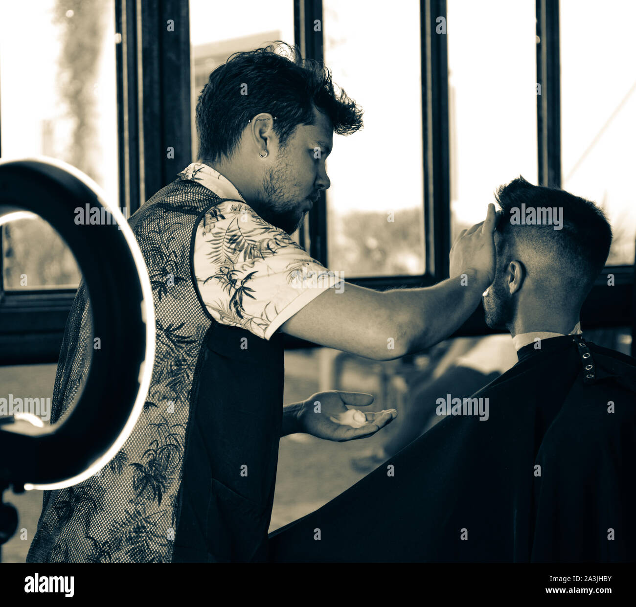 Dopo un nuovo taglio di capelli, barbiere preps un client per una rasatura con l aiuto di una moderna luce ad anello a '81 Barbieri in Tucson, AZ, Stati Uniti d'America Foto Stock