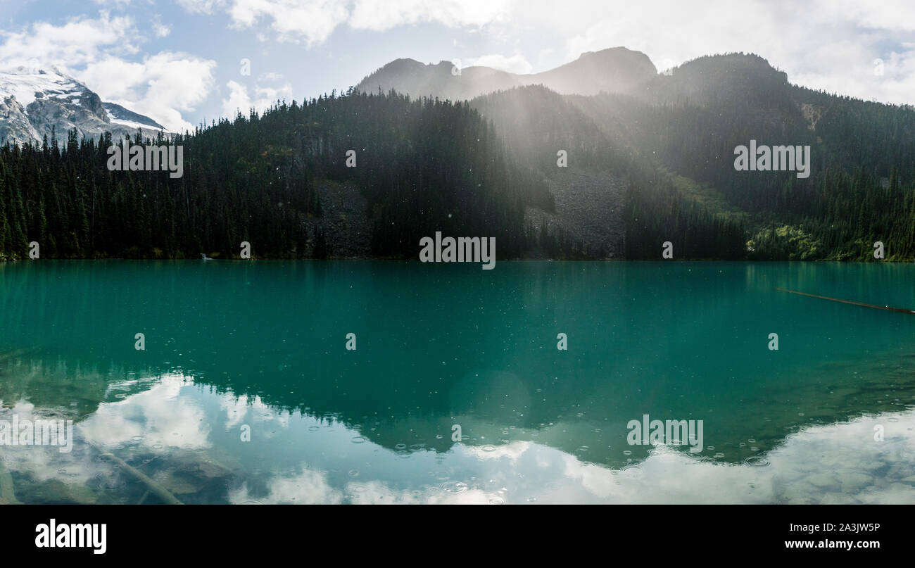 Il sole splende attraverso la pioggia e le nuvole sopra il lago di Joffre. Foto Stock