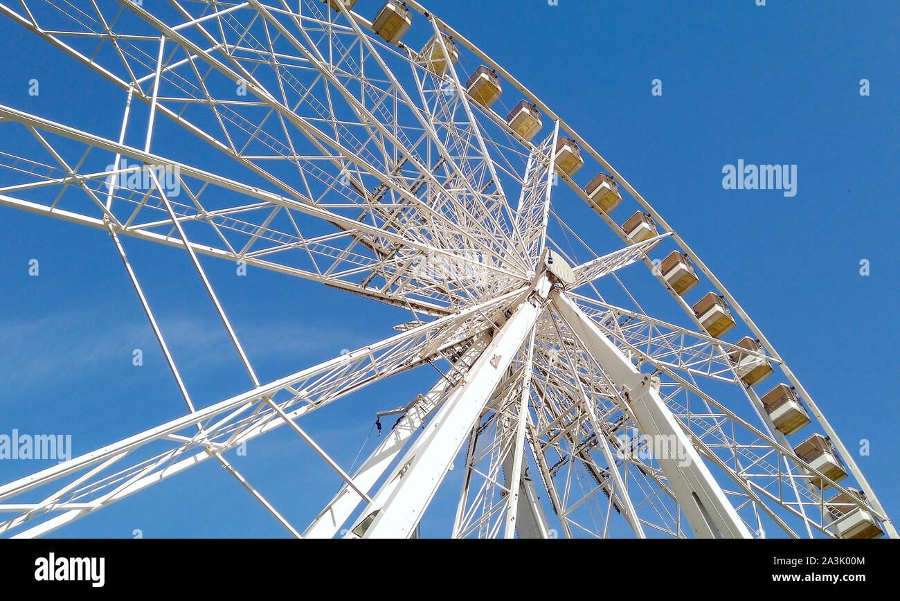 Ruota bianca grande che gira in un parco divertimenti con blu cielo sullo sfondo Foto Stock