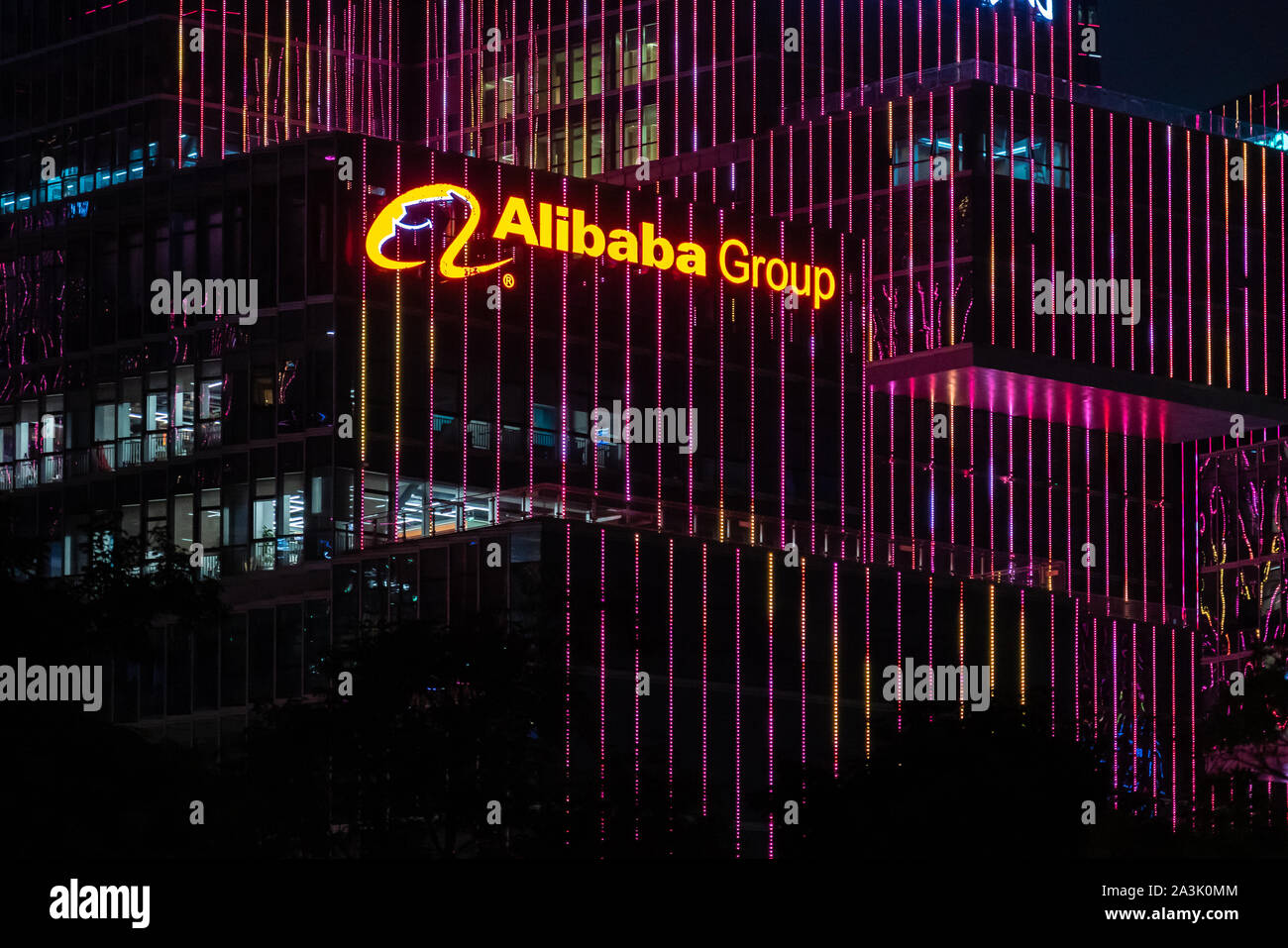 Multinazionale cinese e-commerce, retail, Internet e il conglomerato di tecnologia società holding del Gruppo Alibaba logo che si vede sulla cima di un grattacielo di notte. Foto Stock