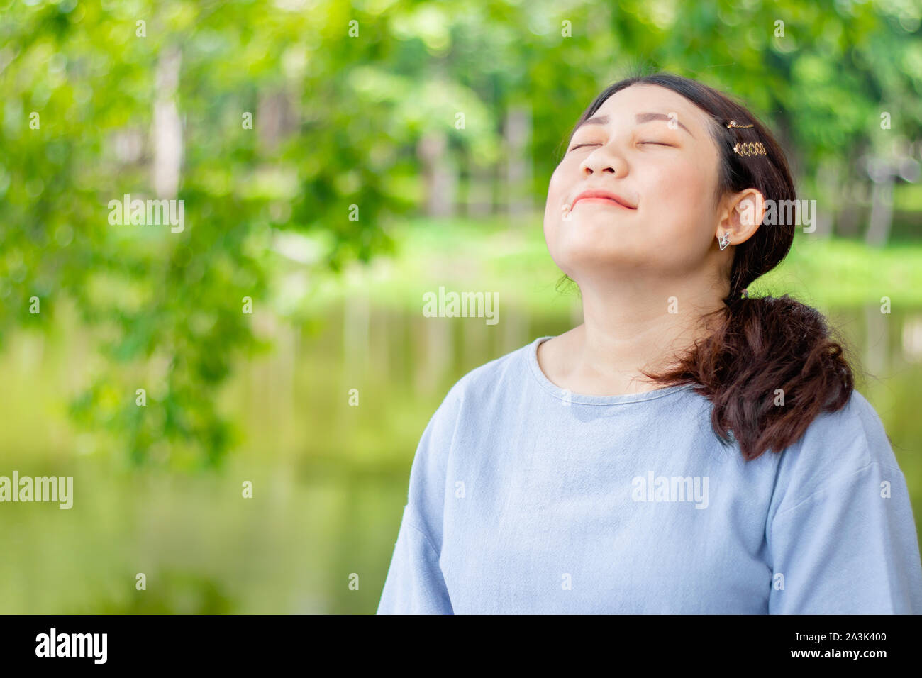 Girl Teen giovane e bella sovradimensionato respirare pienamente fresca e pulita aria di ozono nel verde parco all'aperto Foto Stock