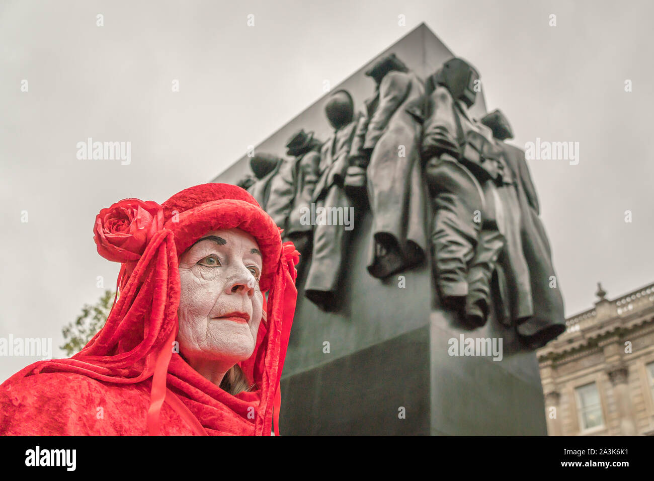Whitehall, Londra, Regno Unito. - 7 Ottobre 2019 - XR ptotests - 'Rosso Brigata" il gruppo di arte, durante una street performance, "Donna della II Guerra Mondiale' in background Foto Stock