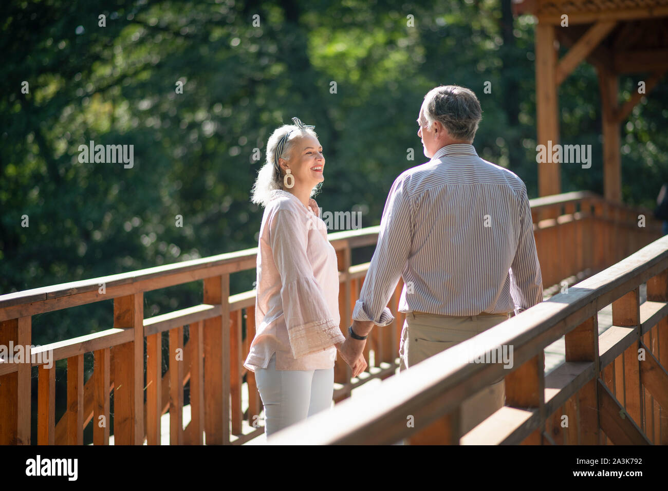 Allegro grey-haired moglie parlando con mio marito mentre si cammina Foto Stock