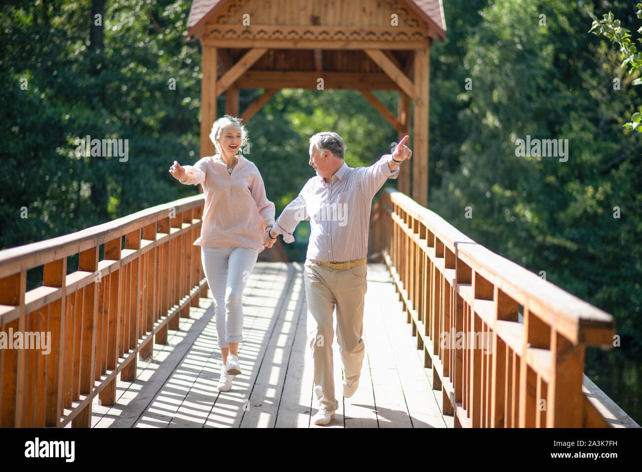 Adulti maturi in esecuzione mentre si attraversa il ponte e la sensazione di essere eccitato Foto Stock