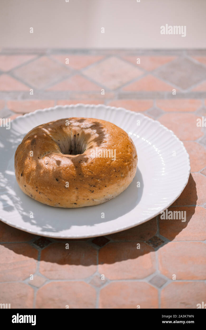 Ciambella sulla piastra bianca su sfondo tabella sotto la luce del sole naturale Foto Stock