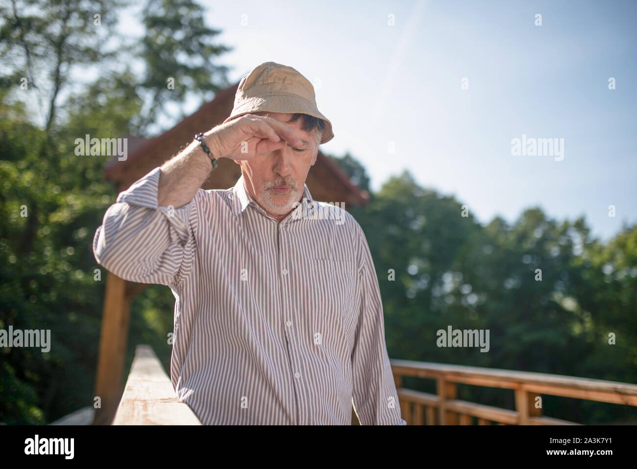 Barbuto uomo maturo indossando estate hat avente mal di testa Foto Stock