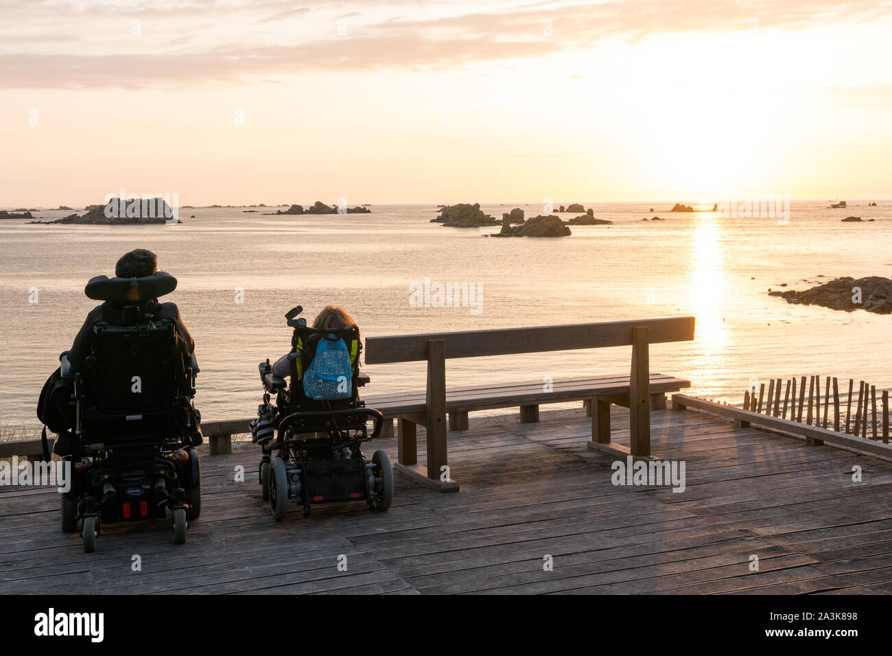 Roscoff, Finisterre / Francia - 21 agosto 2019: due persone in carrozzina godere la possibilità di guardare il tramonto sulla spiaggia e l'oceano Foto Stock
