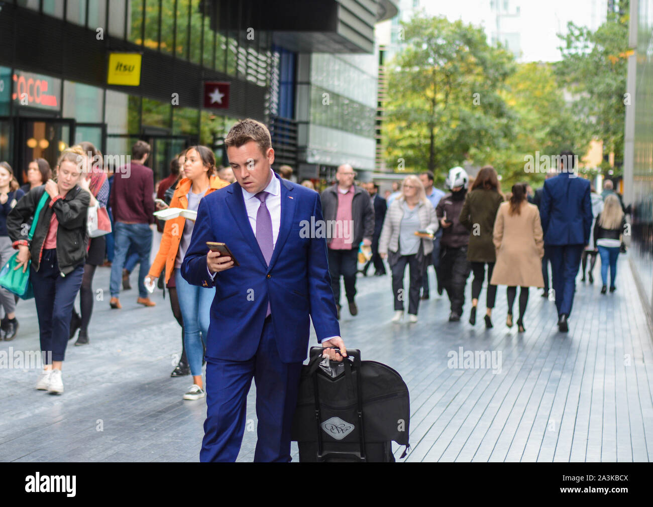 La gente vestita in elegante stile business costumi camminando in office area lavori vicino al Tower Bridge di Londra Foto Stock