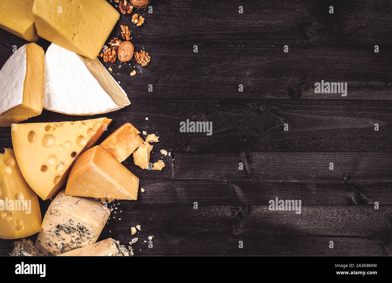 Vari tipi di formaggio in legno nero con sfondo spazio copia. Il Cheddar, parmigiano, emmental, formaggi blu. Vista superiore, foto filtrata in stile vintage Foto Stock