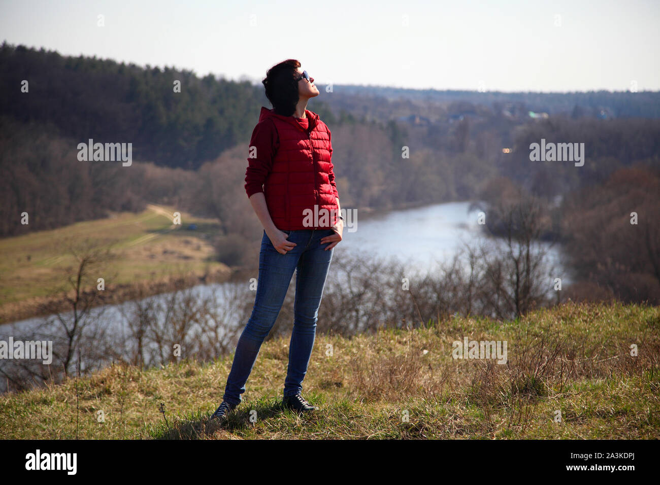 Una ragazza raccoglie snowdrops nella foresta. Bella giovane donna bagna i raggi del sole di primavera in una radura della foresta. Foto Stock