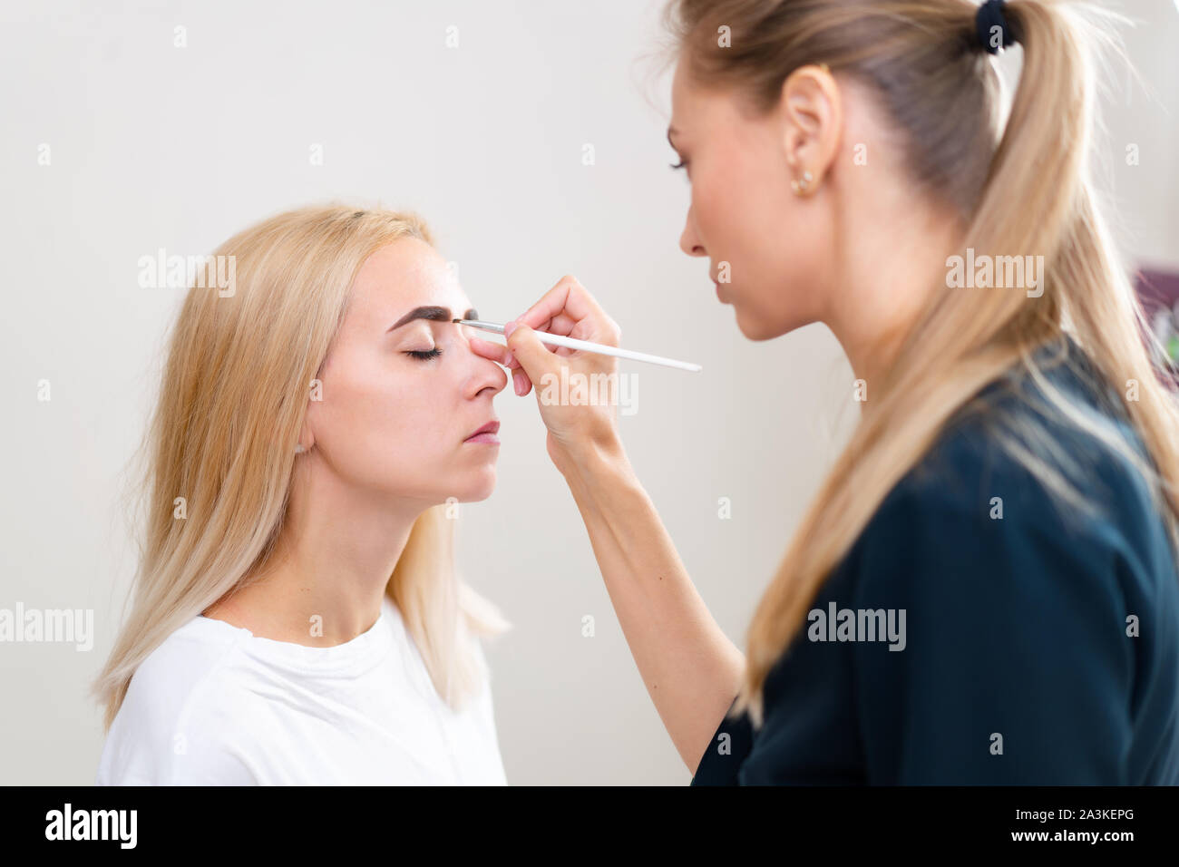 La cosmetologia client cabinet seduto sul divano. Estetista si applica la marcatura sulla sopracciglia. Preparazione per la procedura del sopracciglio permanente del trucco. Free s Foto Stock