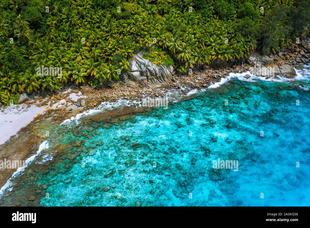 Vista aerea della wild appartata spiaggia solitaria con ruvide rocce di granito, la sabbia bianca e le palme in una giungla e acque turchesi dell'oceano indiano a Foto Stock