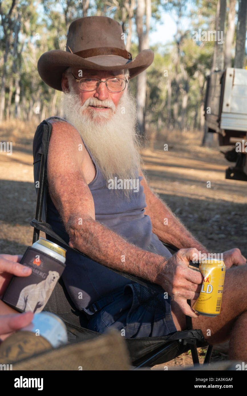Ritratto di un australiano Bushman, con una lunga barba bianca e un cappello da cowboy, tenendo una lattina di birra, Mareeba Aeroporto, Queensland, QLD, Australia Foto Stock