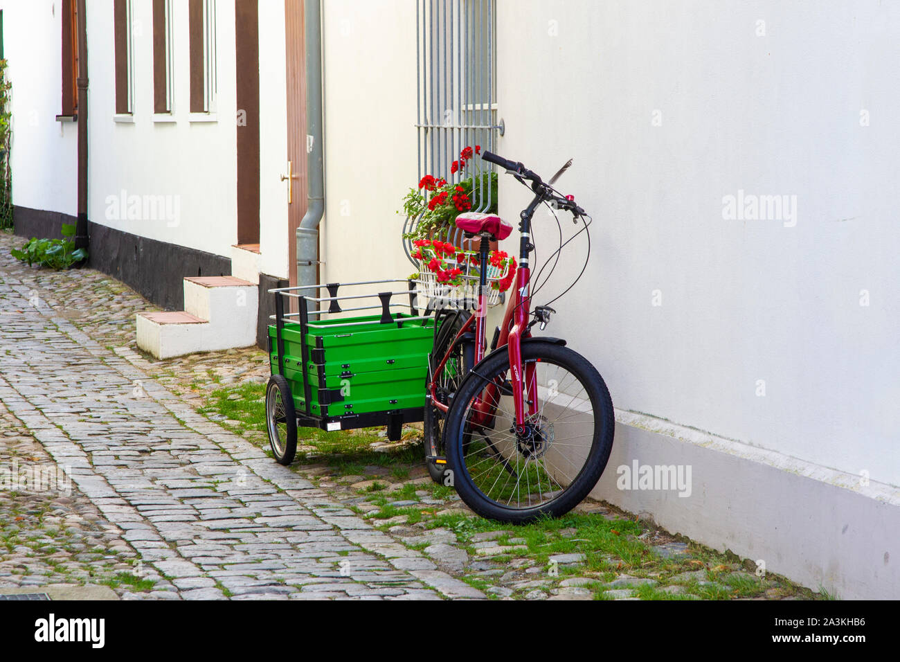 Un pushbike e il carrello al di fuori di una casa in allyway ciottoli nel centro di Warmemunde, Rostock, Germania. Foto Stock