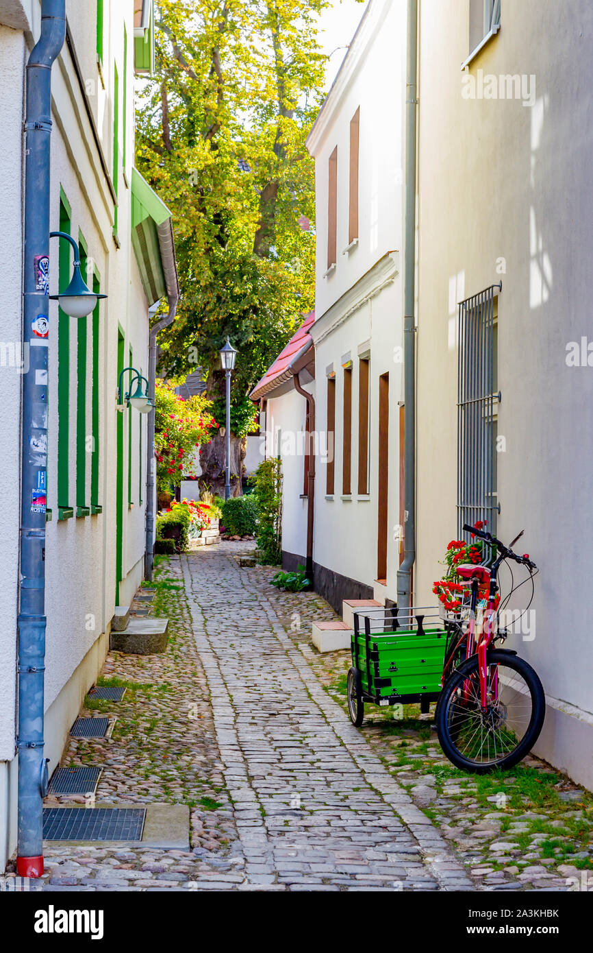 Un pushbike e il carrello al di fuori di una casa in allyway ciottoli nel centro di Warmemunde, Rostock, Germania. Foto Stock