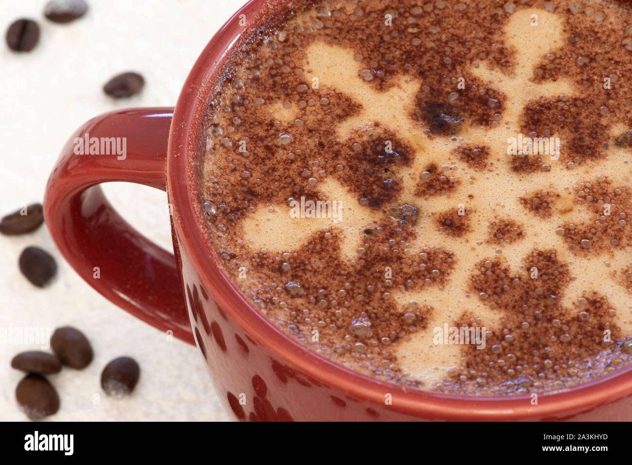 Un cappuccino con il simbolo del fiocco di neve al cioccolato motif, sfondo innevato e la dispersione di chicchi di caffè imposta la scena di una festa di Natale drink strappalacrime Foto Stock