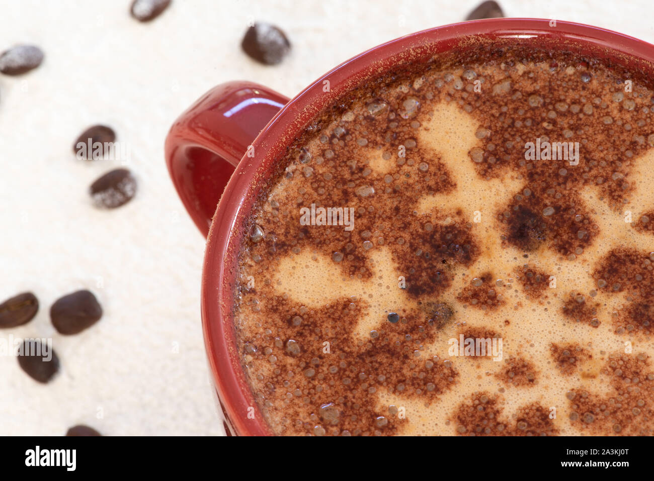Un cappuccino con il simbolo del fiocco di neve al cioccolato motif, sfondo innevato e la dispersione di chicchi di caffè imposta la scena di una festa di Natale drink strappalacrime Foto Stock