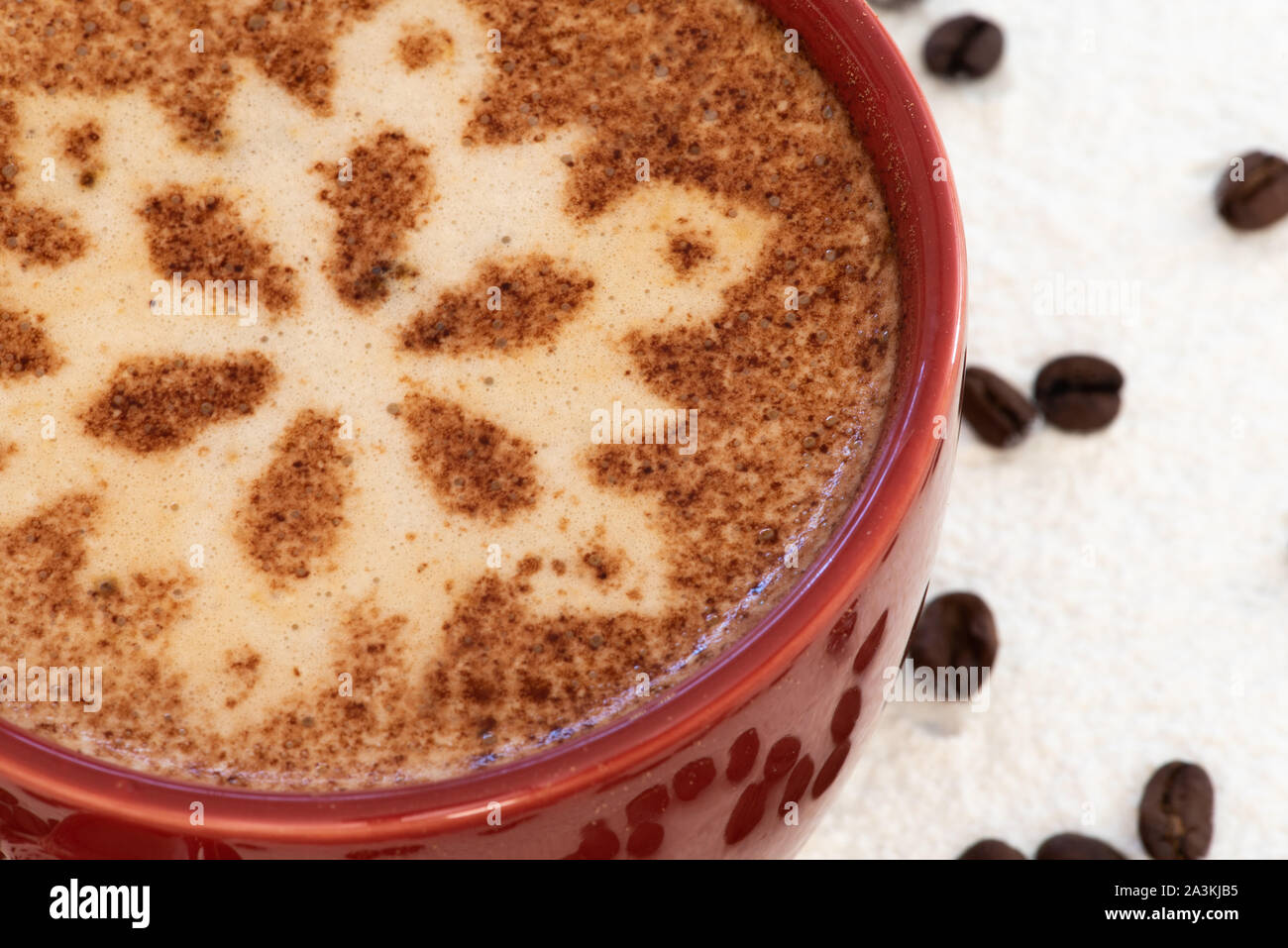 Un cappuccino con il simbolo del fiocco di neve al cioccolato motif, sfondo innevato e la dispersione di chicchi di caffè imposta la scena di una festa di Natale drink strappalacrime Foto Stock