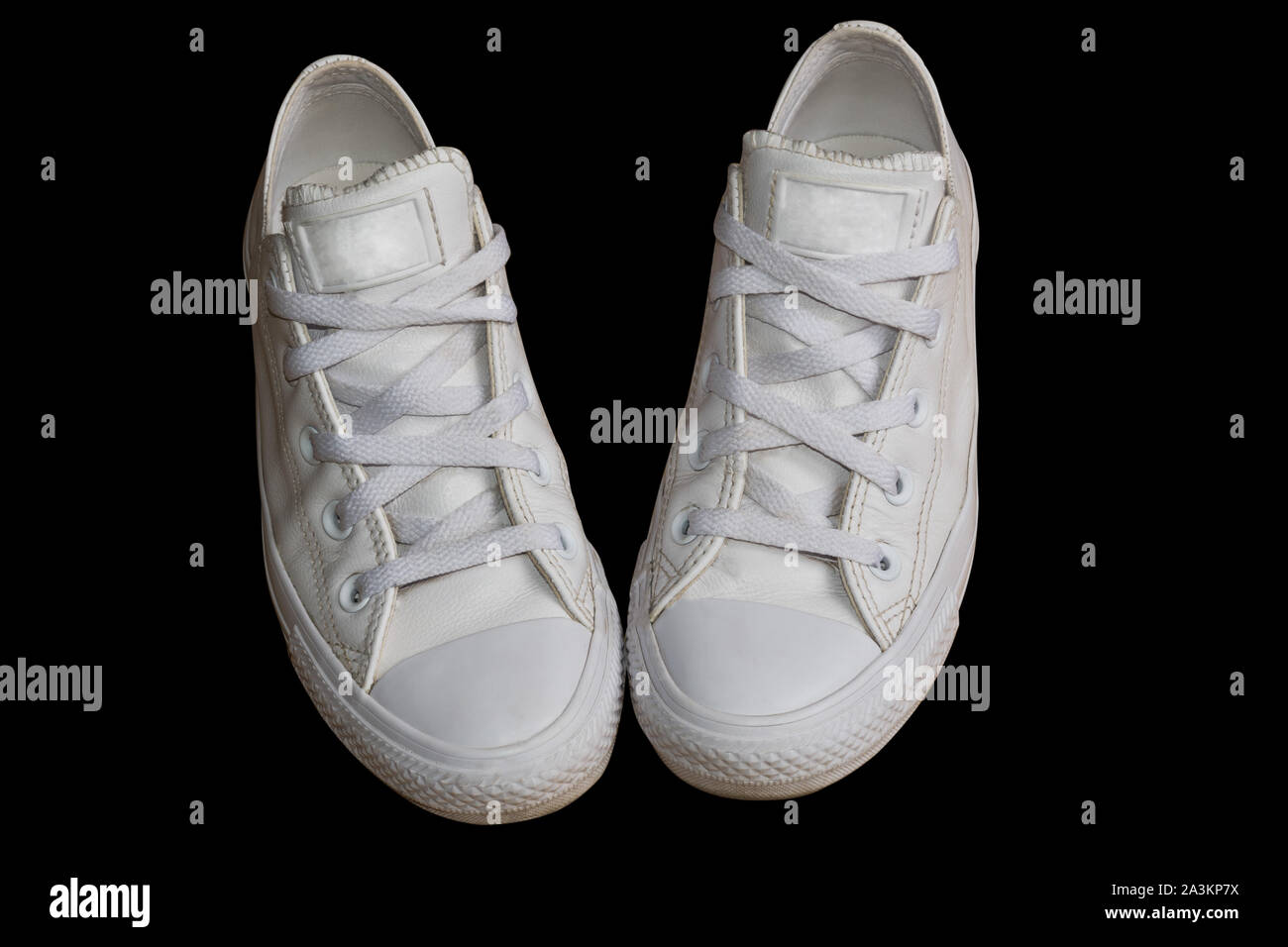 Bianco alla moda in pelle femmina sneakers closeup isolati su sfondo nero. Stile donna calzature casual Foto Stock