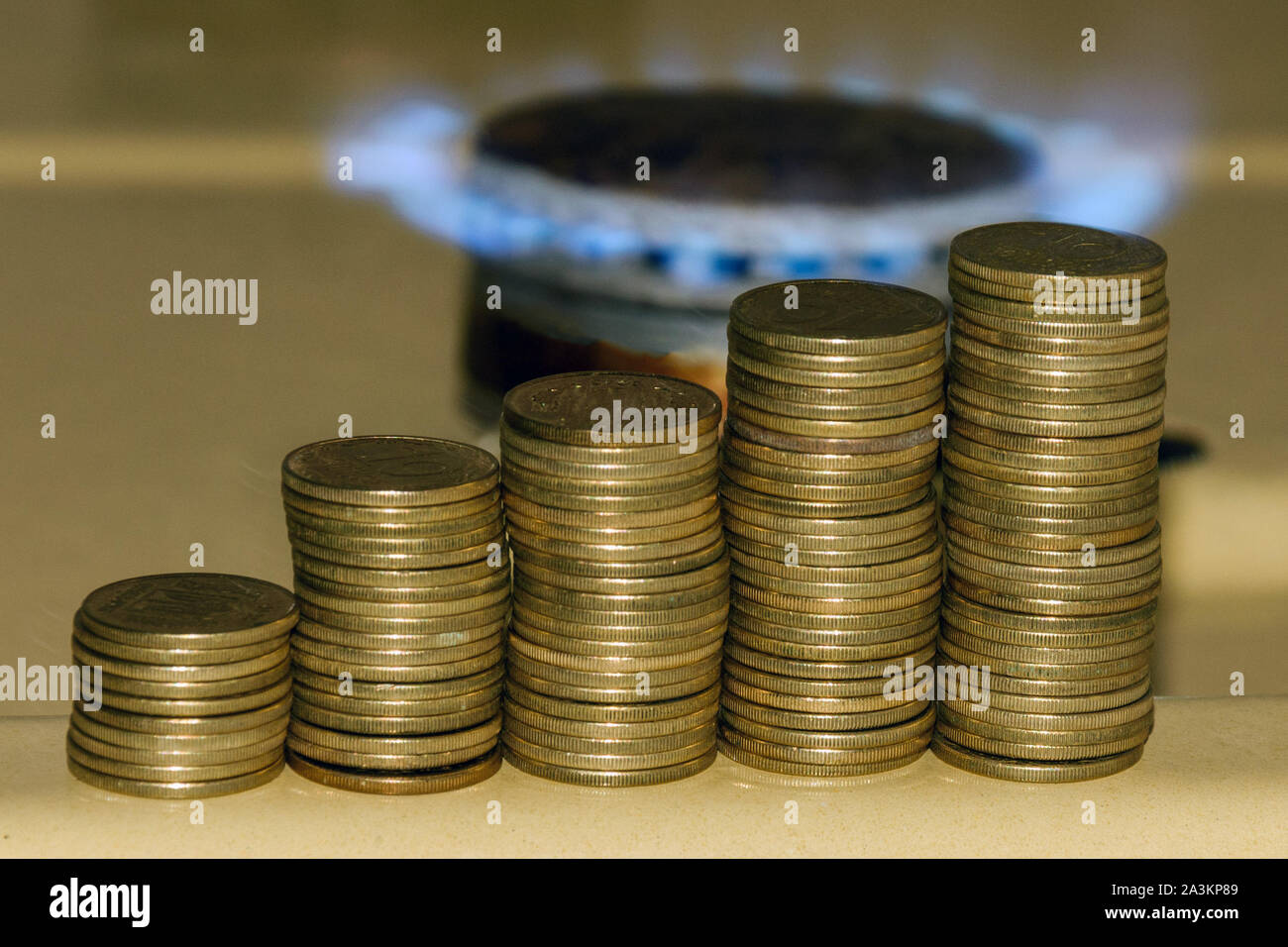 Aumento del prezzo del gas concetto. Blu fiamma a gas e aumentando la pila di monete. Simbolo di aumento dei costi del gas. Foto Stock